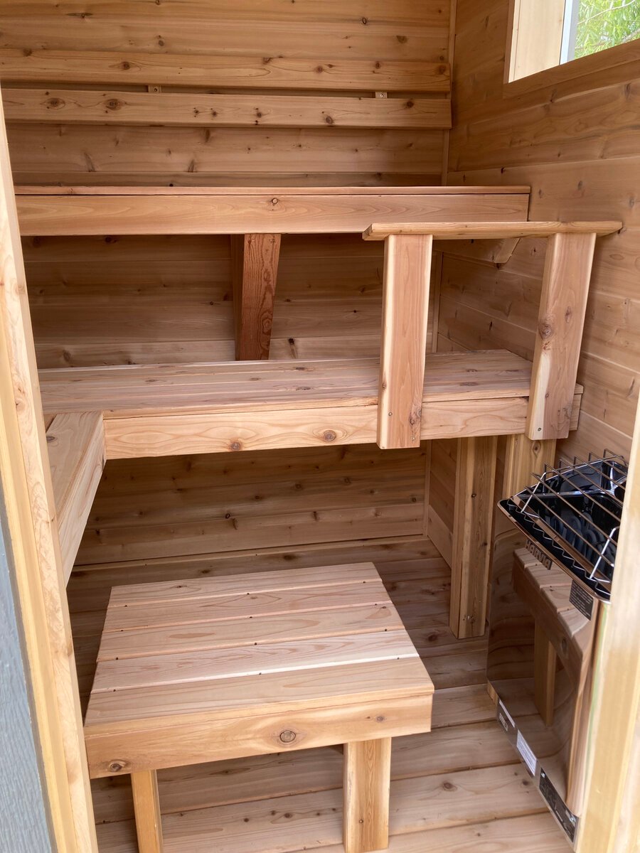 Tiered cedar sauna benches with a heater guard visible